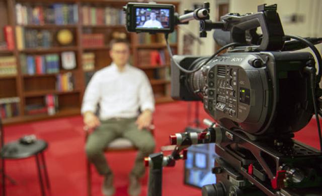 a subject is interviewed with a broadcast camera filming