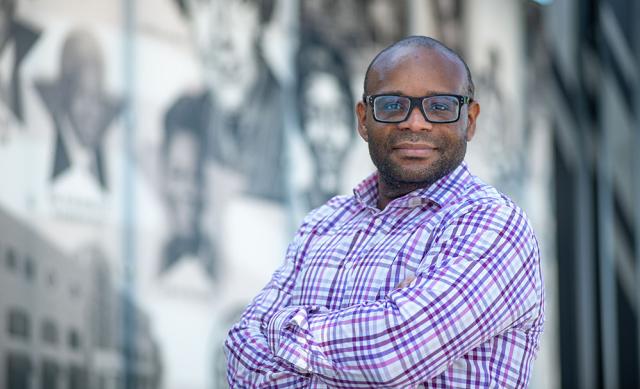 Man with glasses in plaid shirt posing for a camera