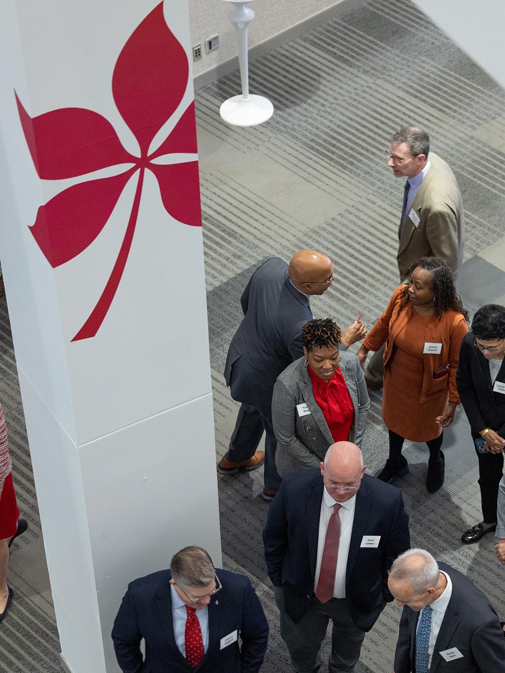 People mingling under a column with a buckeye leaf decal