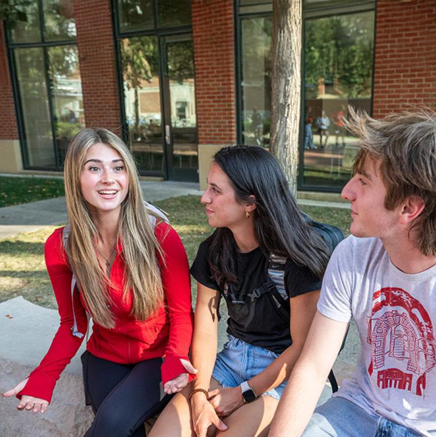 Three students having a discussion outside on campus