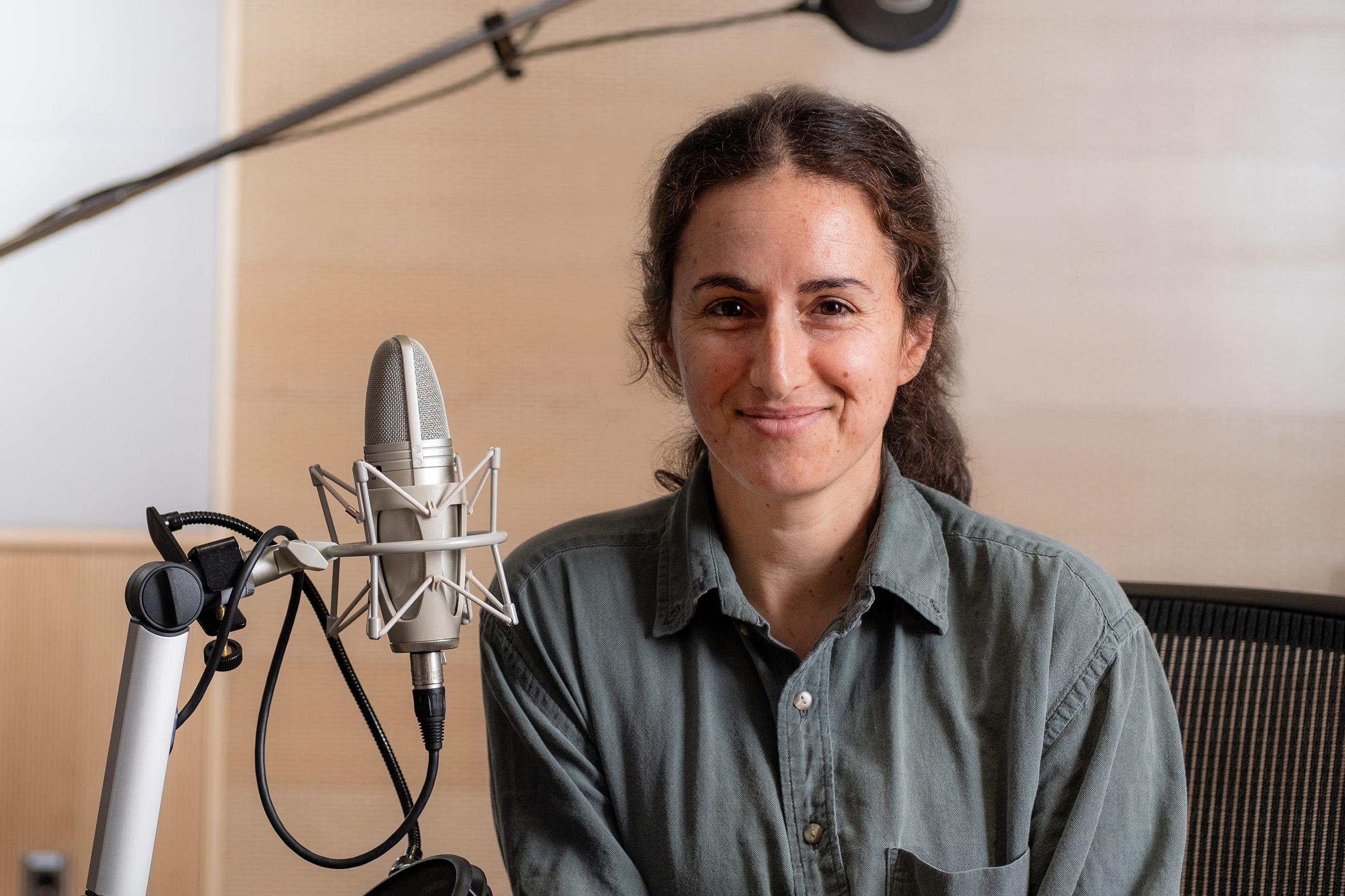 Smiling woman in front of podcast microphone equipment