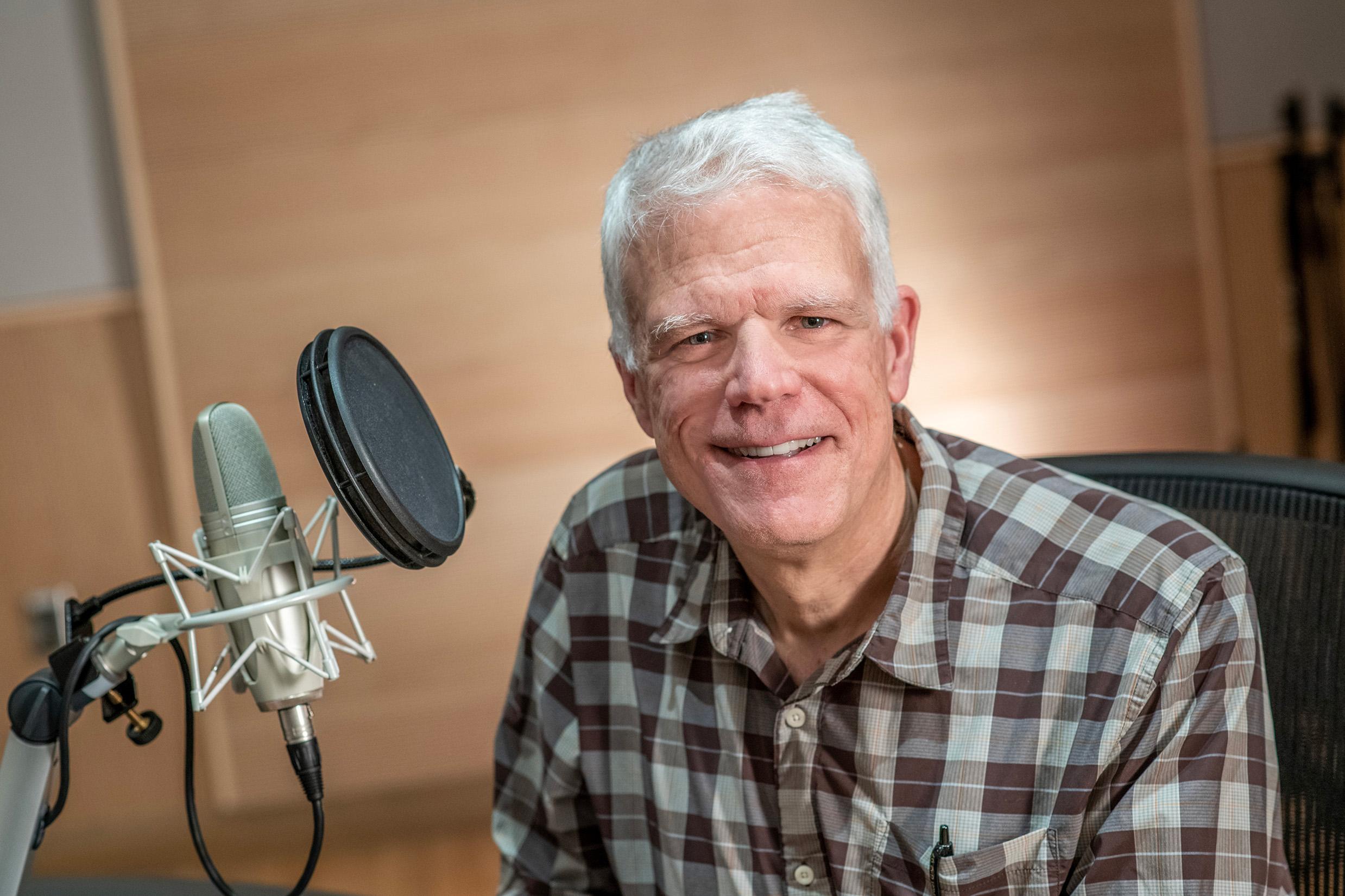 Older man in front of podcast microphone equipment