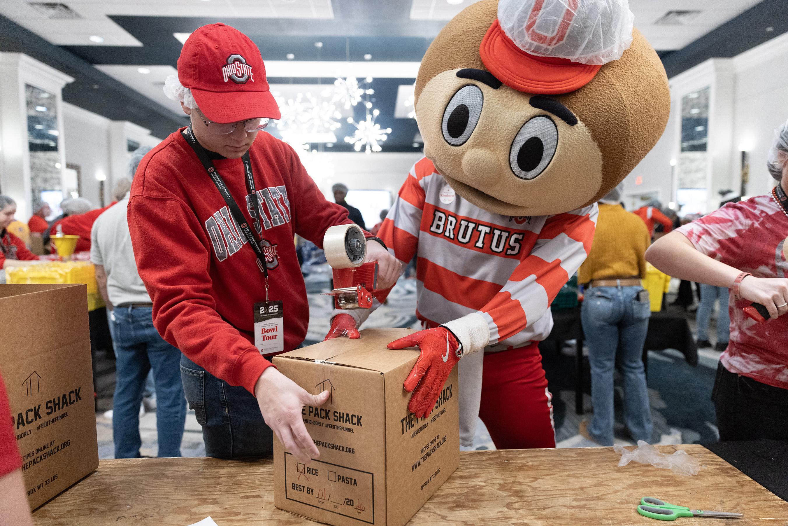 Brutus Buckeye mascot helping volunteers pack boxes