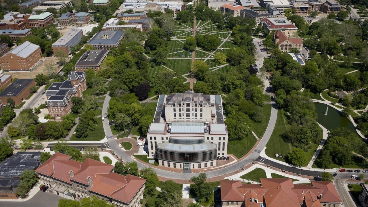 Aerial view of The Ohio State University campus, showing the Oval, Thompson Library, and the College of Engineering. The campus is surrounded by trees and green spaces.