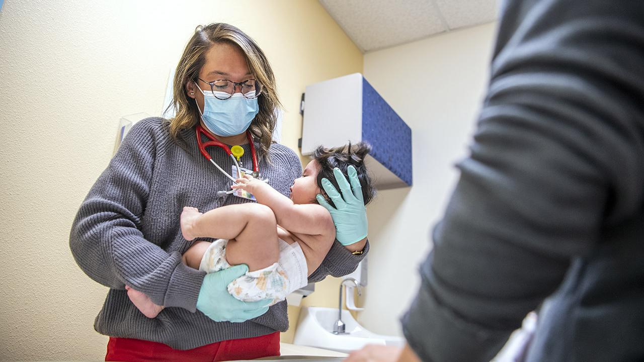 OSAM profile of alumna Dr. Christina Knight, who works as a physician for Indian Health Services on the Navajo Nation. Performing an exam on a baby with her mother