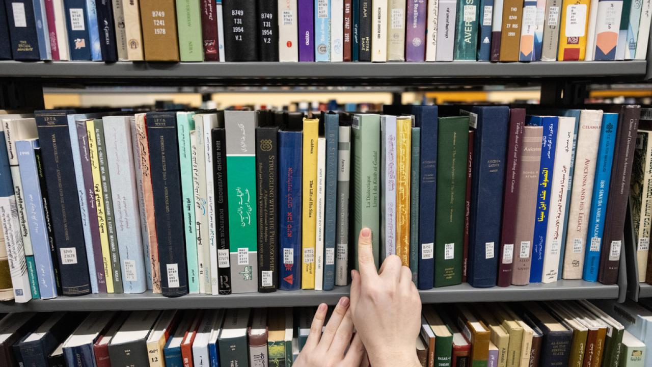 Hands pulling a book off library shelf