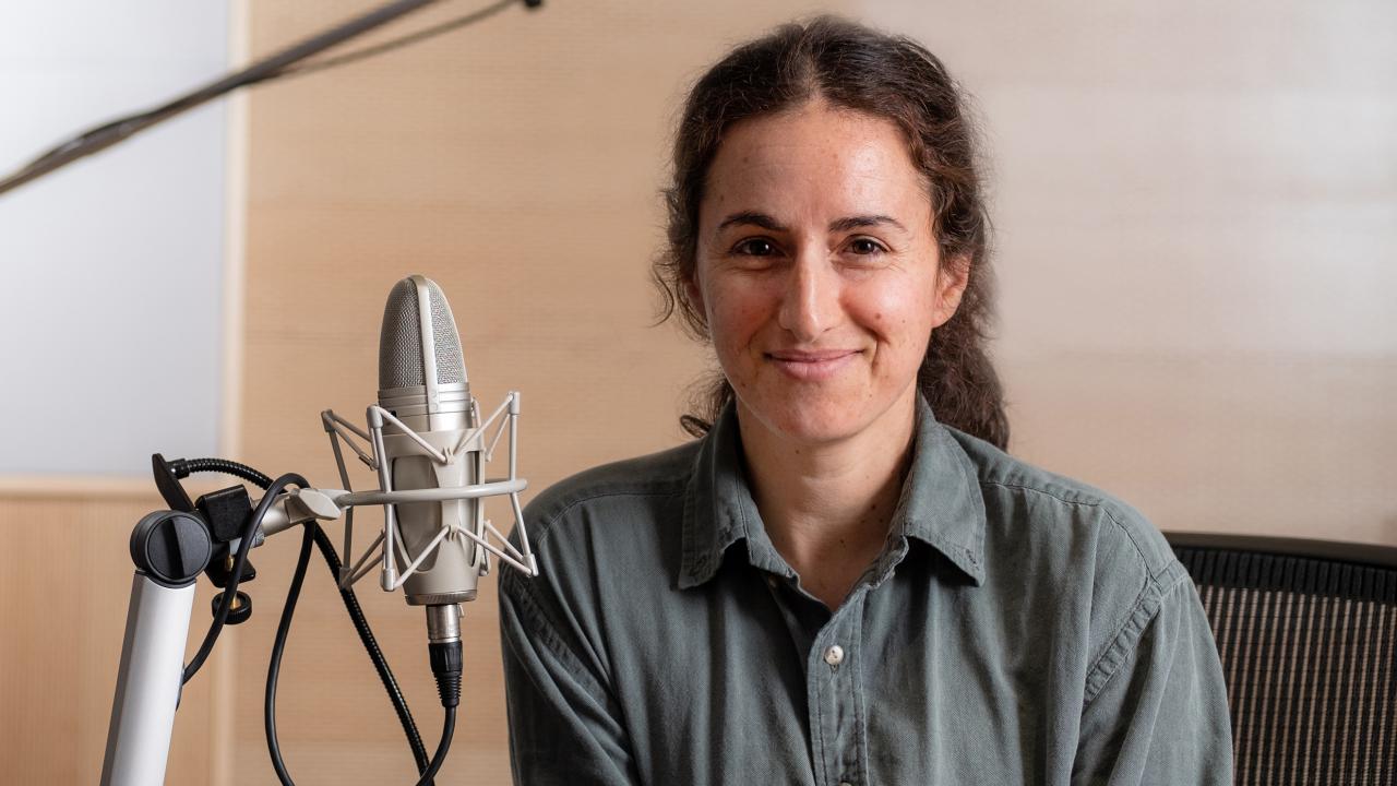 Smiling woman in front of podcast microphone equipment