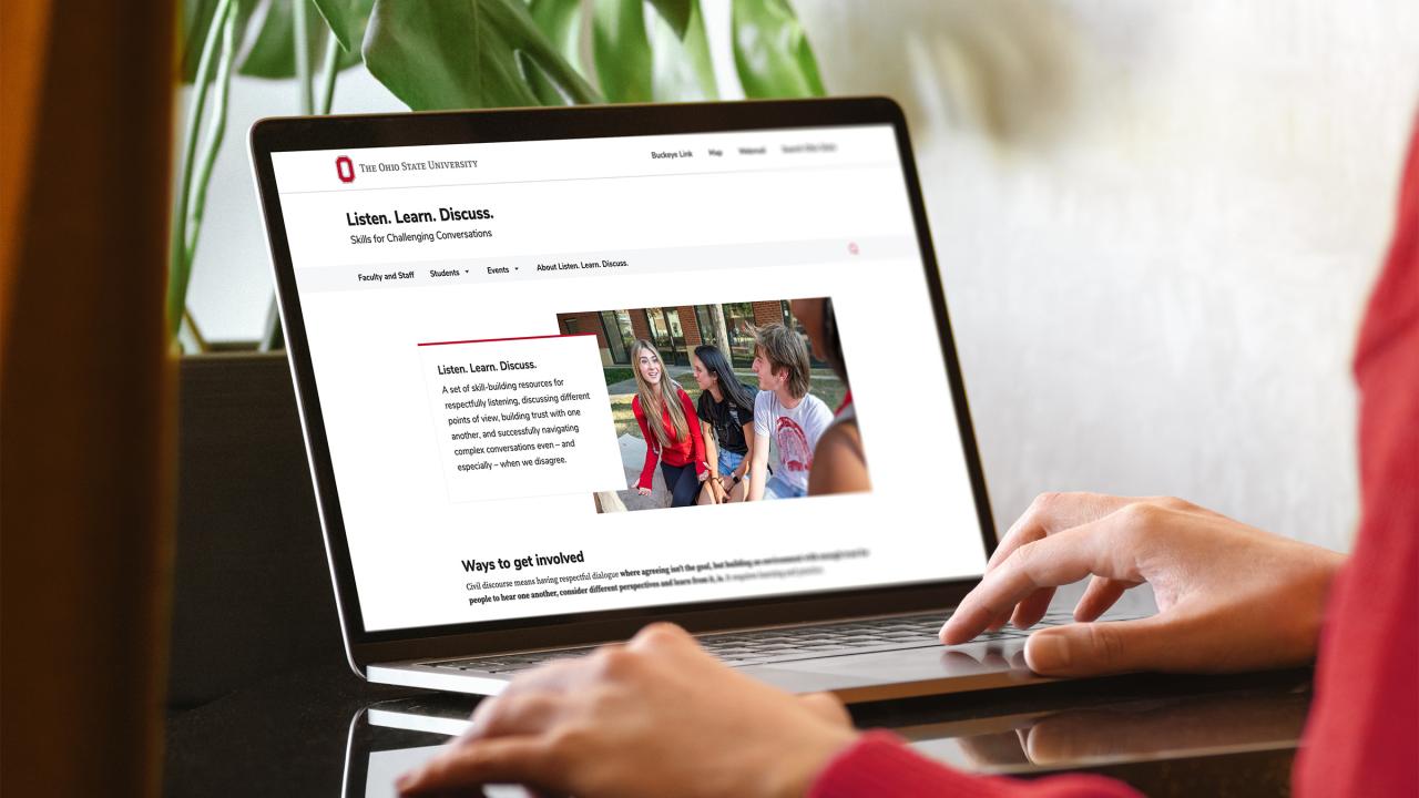 Woman in red sweater using laptop with Listen Learn Discuss website pulled up