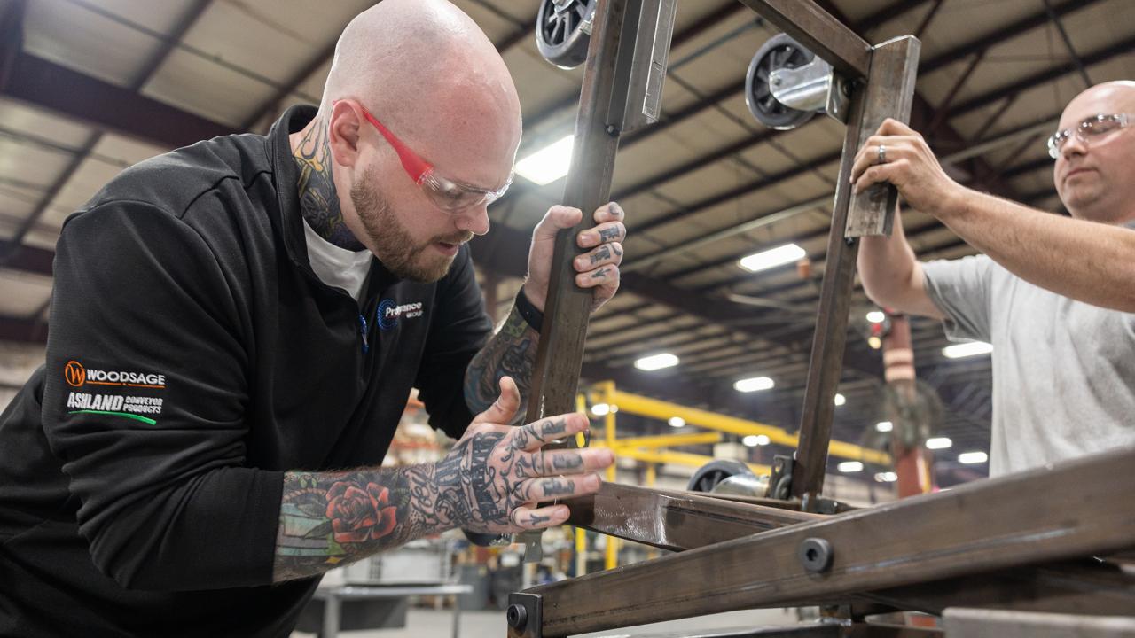 Zack Ernest and another man work with machinery.